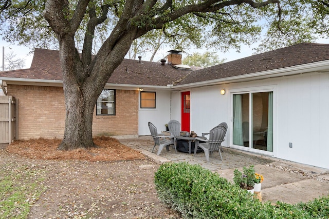 rear view of property featuring an outdoor fire pit and a patio area