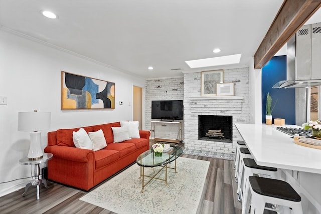 living room featuring ornamental molding, a brick fireplace, a skylight, and light hardwood / wood-style flooring