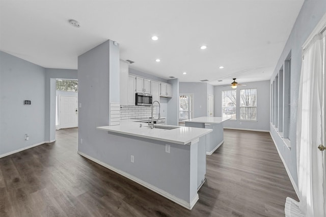 kitchen with a breakfast bar, white cabinetry, sink, decorative backsplash, and kitchen peninsula