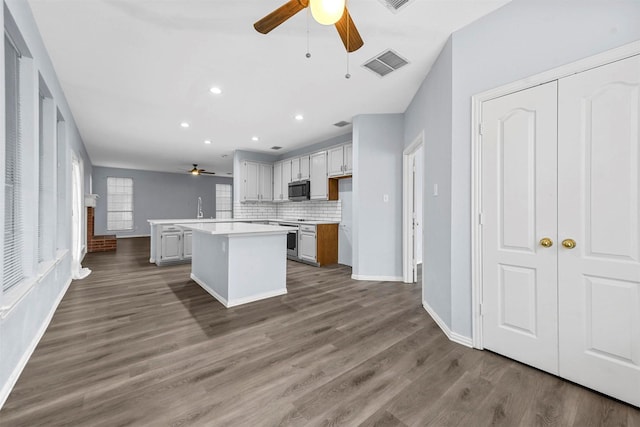 kitchen featuring hardwood / wood-style flooring, ceiling fan, a kitchen island, and backsplash