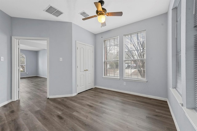 unfurnished bedroom with dark wood-type flooring, a closet, and multiple windows