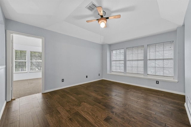 unfurnished room featuring ceiling fan, dark hardwood / wood-style flooring, and a tray ceiling