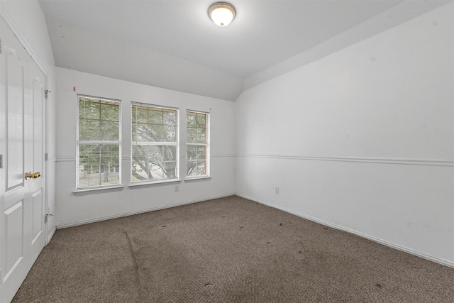 unfurnished room featuring lofted ceiling and carpet flooring