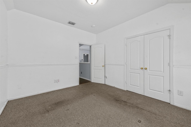 unfurnished bedroom featuring vaulted ceiling, dark carpet, and a closet