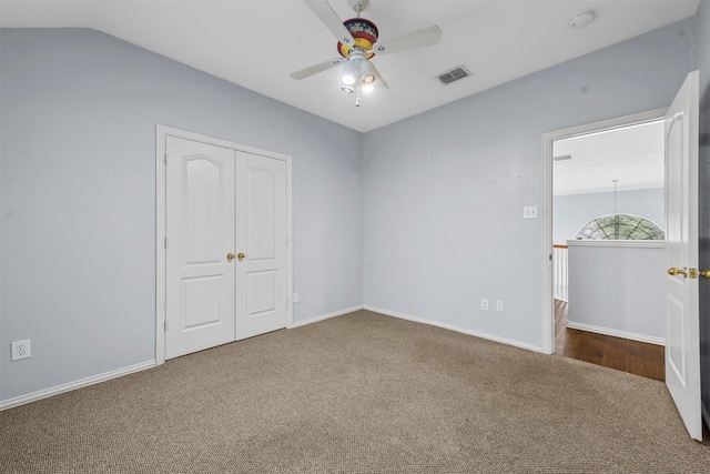 unfurnished bedroom featuring lofted ceiling, a closet, ceiling fan, and carpet flooring