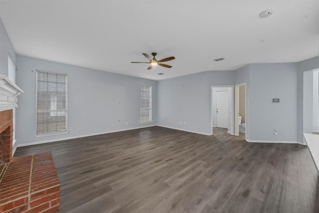 unfurnished living room featuring ceiling fan, dark wood-type flooring, and a fireplace