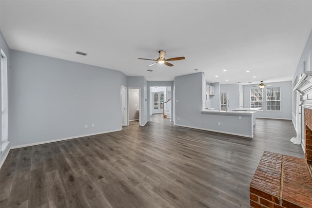 unfurnished living room featuring dark hardwood / wood-style flooring, sink, a fireplace, and ceiling fan