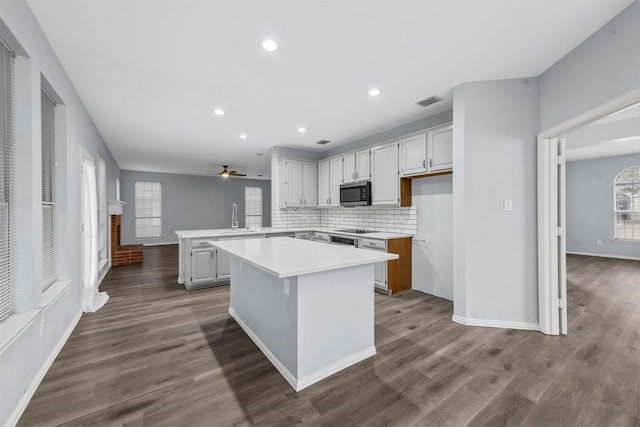 kitchen featuring white cabinetry, a center island, tasteful backsplash, wood-type flooring, and kitchen peninsula