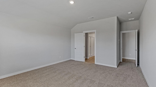 unfurnished bedroom featuring light carpet and lofted ceiling