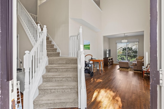 stairway with wood-type flooring and a high ceiling