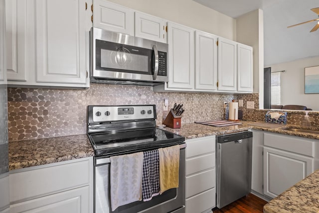 kitchen featuring appliances with stainless steel finishes, tasteful backsplash, dark stone countertops, white cabinets, and ceiling fan