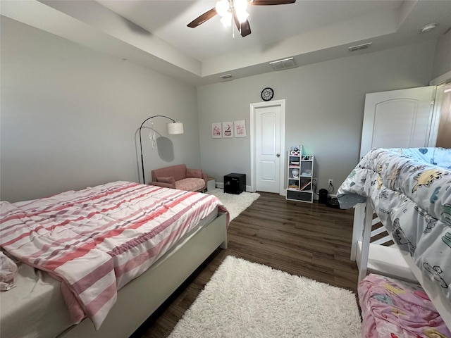 bedroom featuring a raised ceiling, dark hardwood / wood-style floors, and ceiling fan