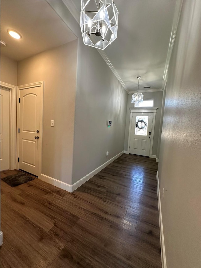 entrance foyer with dark hardwood / wood-style flooring, a notable chandelier, and ornamental molding