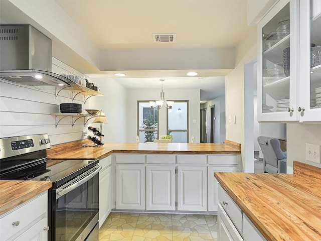 kitchen featuring extractor fan, white cabinetry, butcher block counters, hanging light fixtures, and stainless steel electric range