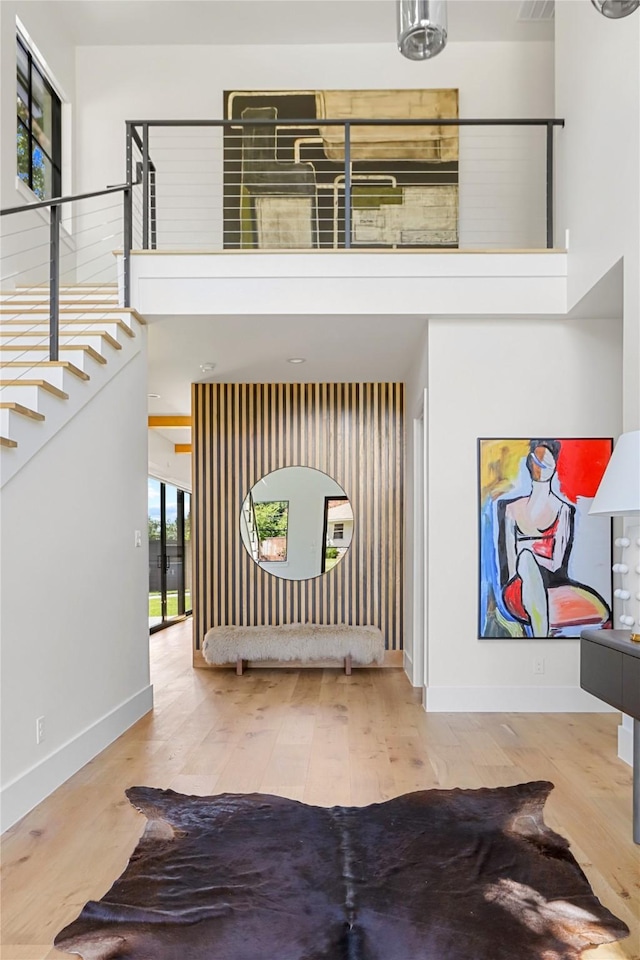 foyer entrance with wood-type flooring and a towering ceiling