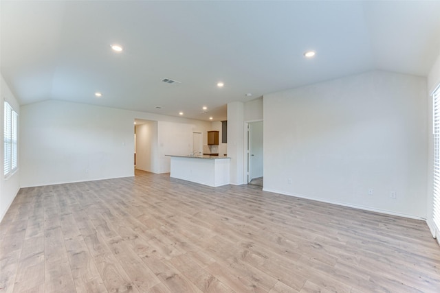 unfurnished living room featuring vaulted ceiling and light wood-type flooring