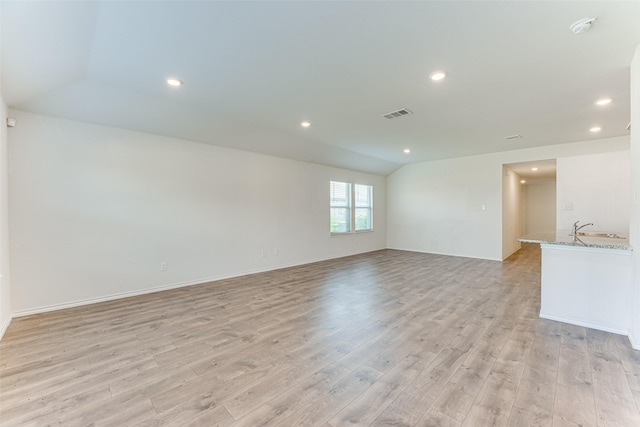 unfurnished room featuring lofted ceiling and light wood-type flooring