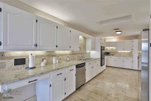 kitchen featuring white cabinetry, sink, stainless steel appliances, and light stone countertops