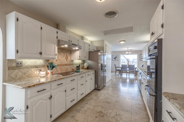 kitchen featuring white cabinetry, light stone counters, black electric cooktop, stainless steel fridge, and backsplash