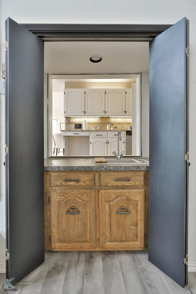 bathroom with wood-type flooring, sink, and decorative backsplash