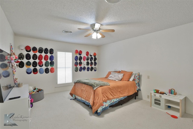 bedroom featuring carpet flooring, a textured ceiling, and ceiling fan