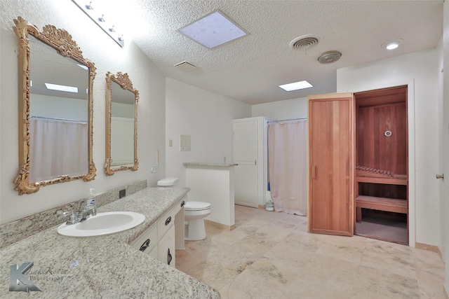 bathroom with vanity, a textured ceiling, and toilet