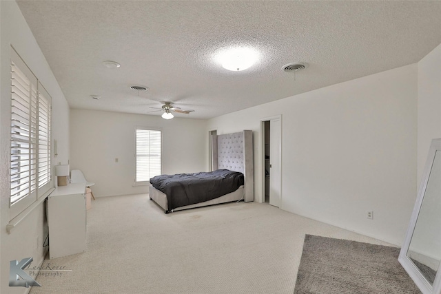 carpeted bedroom featuring ceiling fan and a textured ceiling