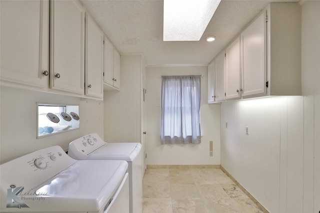 washroom with cabinets, separate washer and dryer, a textured ceiling, and a skylight