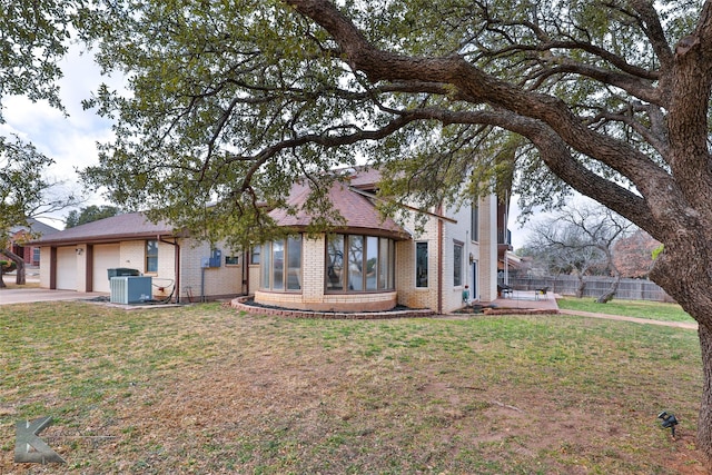 view of front of house featuring central AC unit, a garage, and a front yard