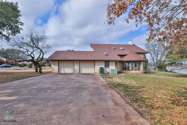 view of front of house with a garage, central AC unit, and a front yard