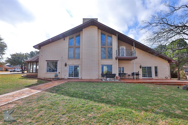 back of house featuring a balcony, a patio area, and a lawn