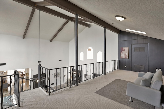 interior space with carpet flooring, a textured ceiling, and vaulted ceiling with beams