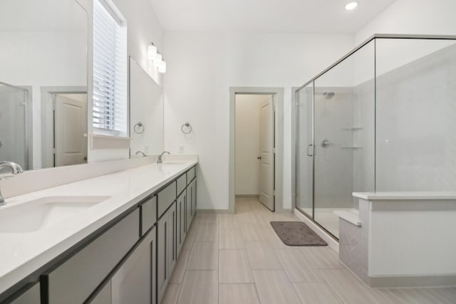 bathroom featuring a stall shower, a sink, baseboards, and double vanity