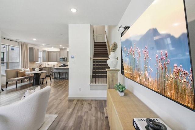 living area featuring stairs, baseboards, wood finished floors, and recessed lighting