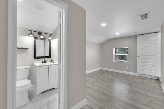 bathroom featuring lofted ceiling, toilet, a textured ceiling, vanity, and hardwood / wood-style floors