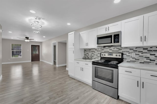 kitchen featuring white cabinetry, stainless steel appliances, light stone counters, tasteful backsplash, and light wood-type flooring