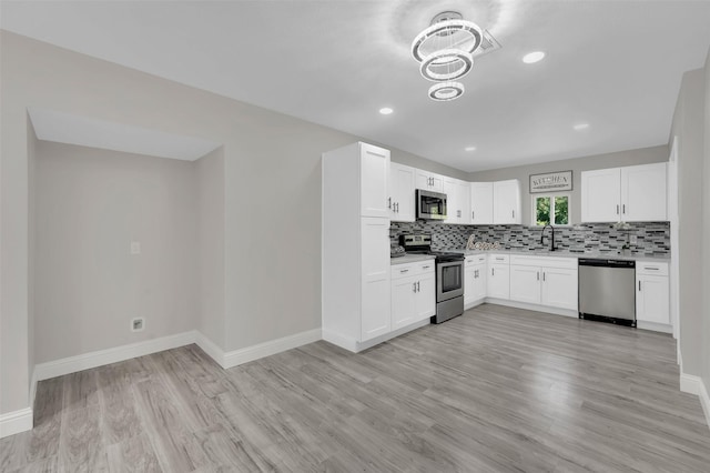 kitchen with sink, appliances with stainless steel finishes, white cabinets, decorative backsplash, and light wood-type flooring