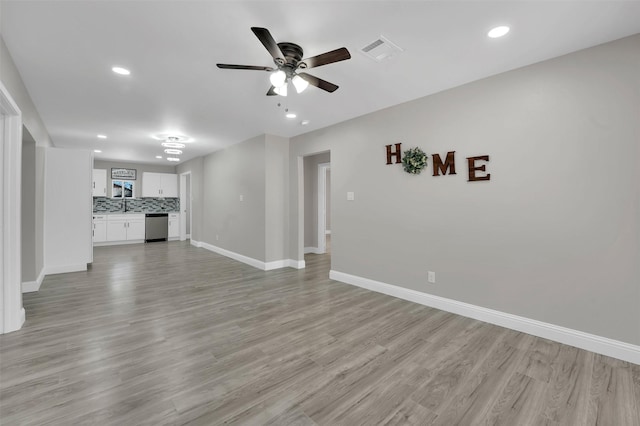 unfurnished living room with sink, light hardwood / wood-style floors, and ceiling fan