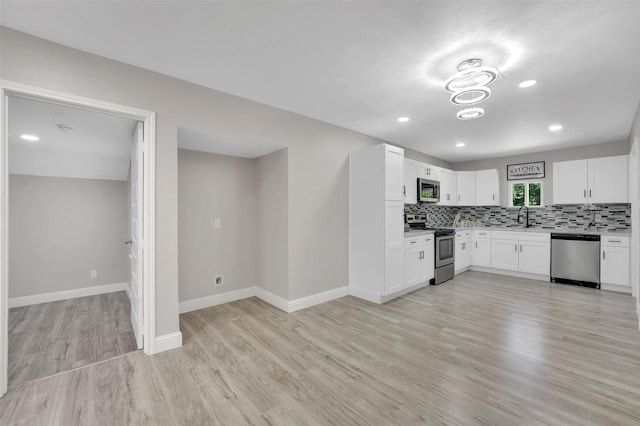 kitchen featuring white cabinetry, appliances with stainless steel finishes, backsplash, and light hardwood / wood-style flooring