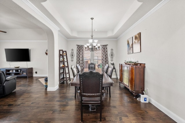 dining area with dark hardwood / wood-style flooring, a tray ceiling, and a chandelier