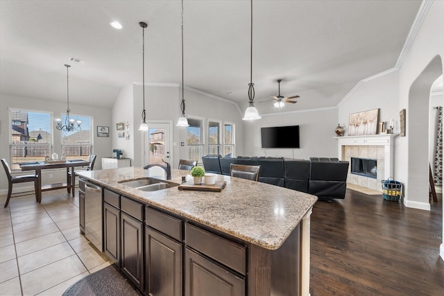 kitchen featuring visible vents, a tiled fireplace, ornamental molding, vaulted ceiling, and a sink