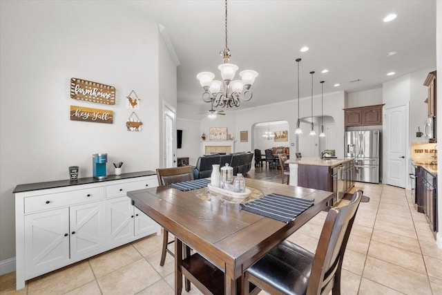 dining room with crown molding, light tile patterned floors, recessed lighting, an inviting chandelier, and arched walkways