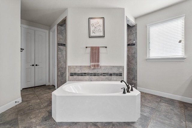 full bathroom with a garden tub and baseboards