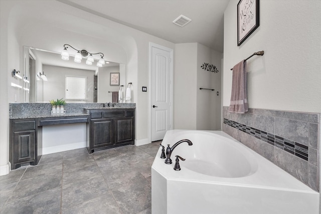 full bathroom featuring visible vents, baseboards, a garden tub, and vanity