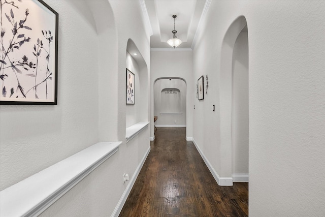 corridor with baseboards, arched walkways, dark wood finished floors, and crown molding