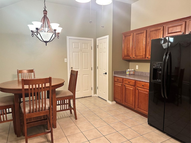 kitchen with pendant lighting, high vaulted ceiling, a chandelier, light tile patterned floors, and black refrigerator with ice dispenser