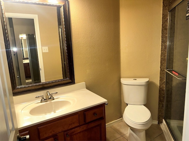 bathroom with vanity, a shower with shower door, tile patterned floors, and toilet