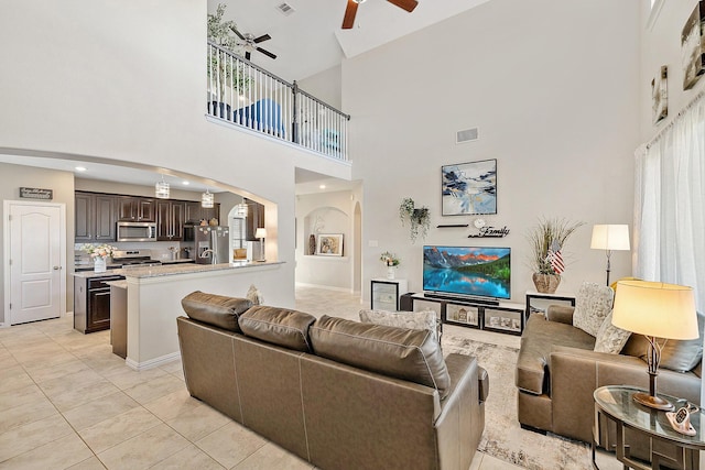 tiled living room with a high ceiling and ceiling fan