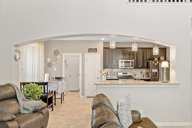 kitchen featuring stainless steel appliances, light tile patterned flooring, and a towering ceiling