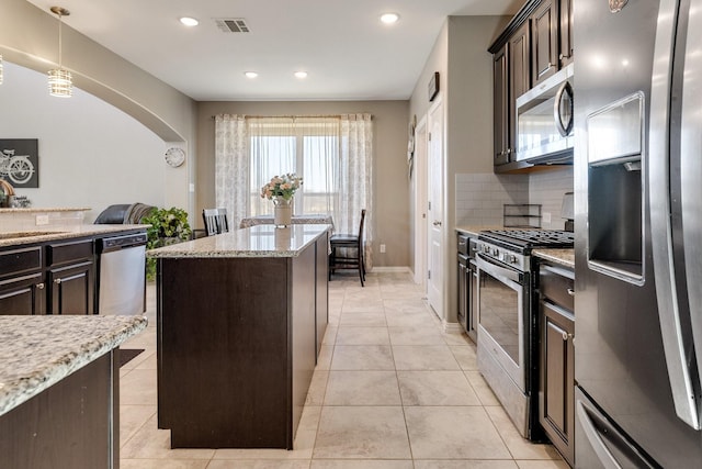 kitchen with a kitchen island, pendant lighting, decorative backsplash, stainless steel appliances, and light stone countertops